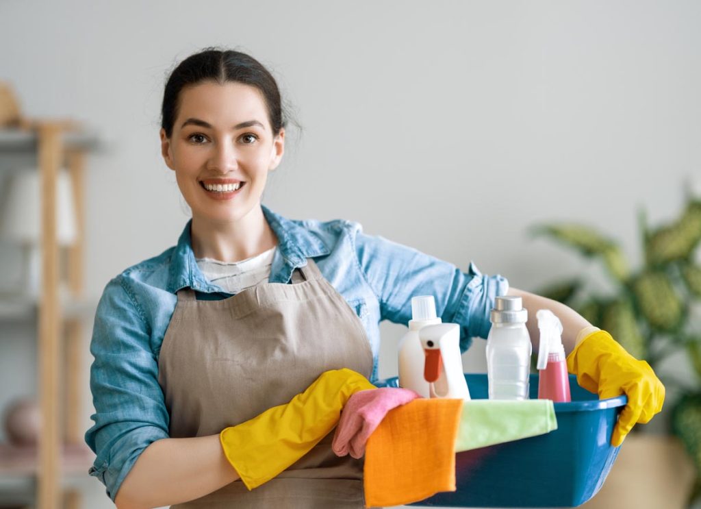Femme va faire le ménage avec beaucoup de produits