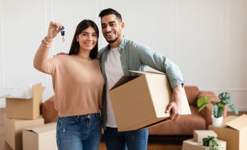 Couple Homme Femme Qui Emménage Dans Une Maison, Cartons, Désordre. La Femme Montre Ses Clefs