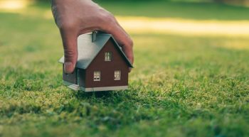 Main Qui Pose Une Maquette De Maison Sur Un Terrain