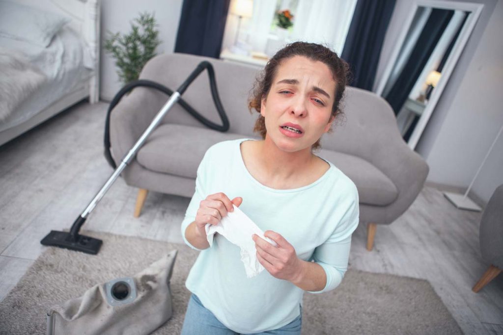 femme ayant des allergies à la poussière en faisant le menage