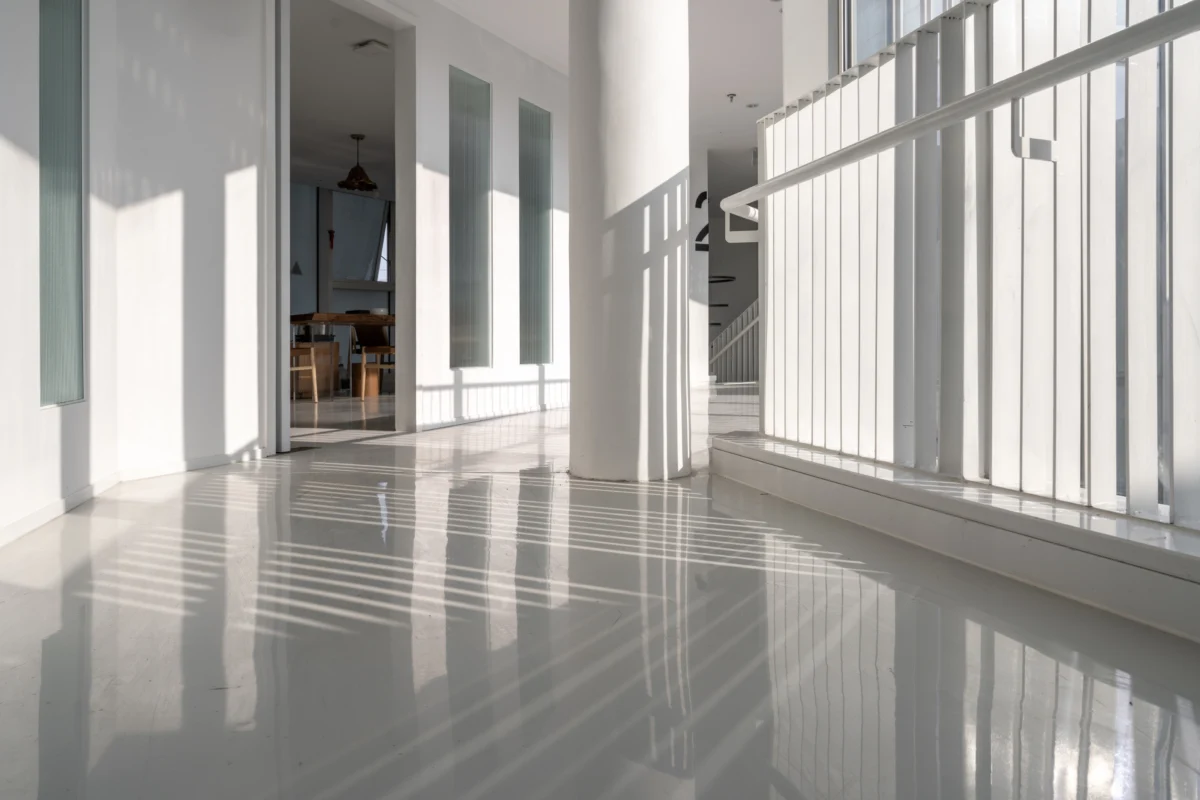 Le soleil se reflète à travers les vitres, illuminant un sol en béton parfaitement ciré.