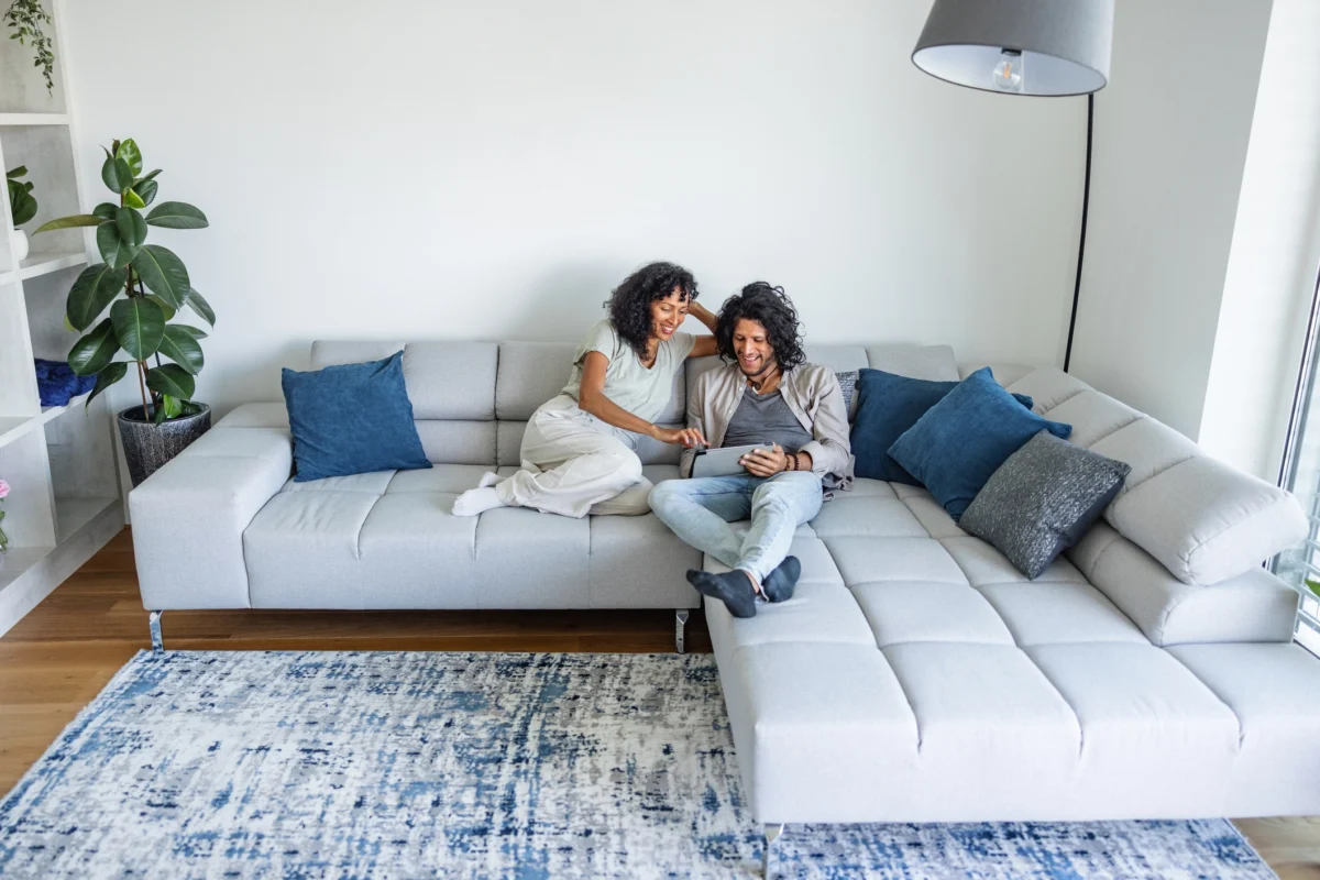 Un couple multiracial de mid-adultes utilise une tablette numérique sur un canapé convertible