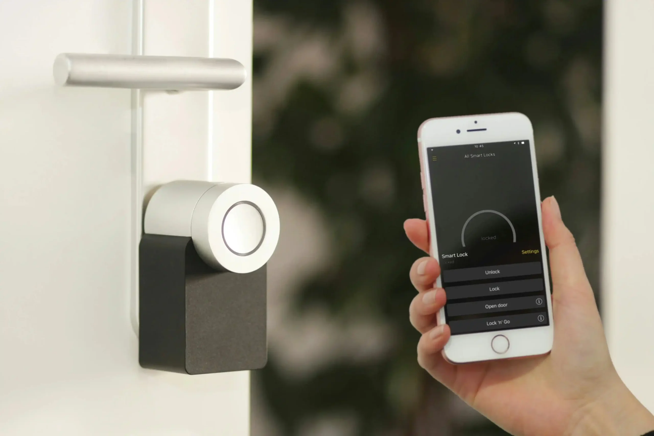 Une main tient un smartphone affichant une application de contrôle à distance devant une serrure électronique installée sur une porte