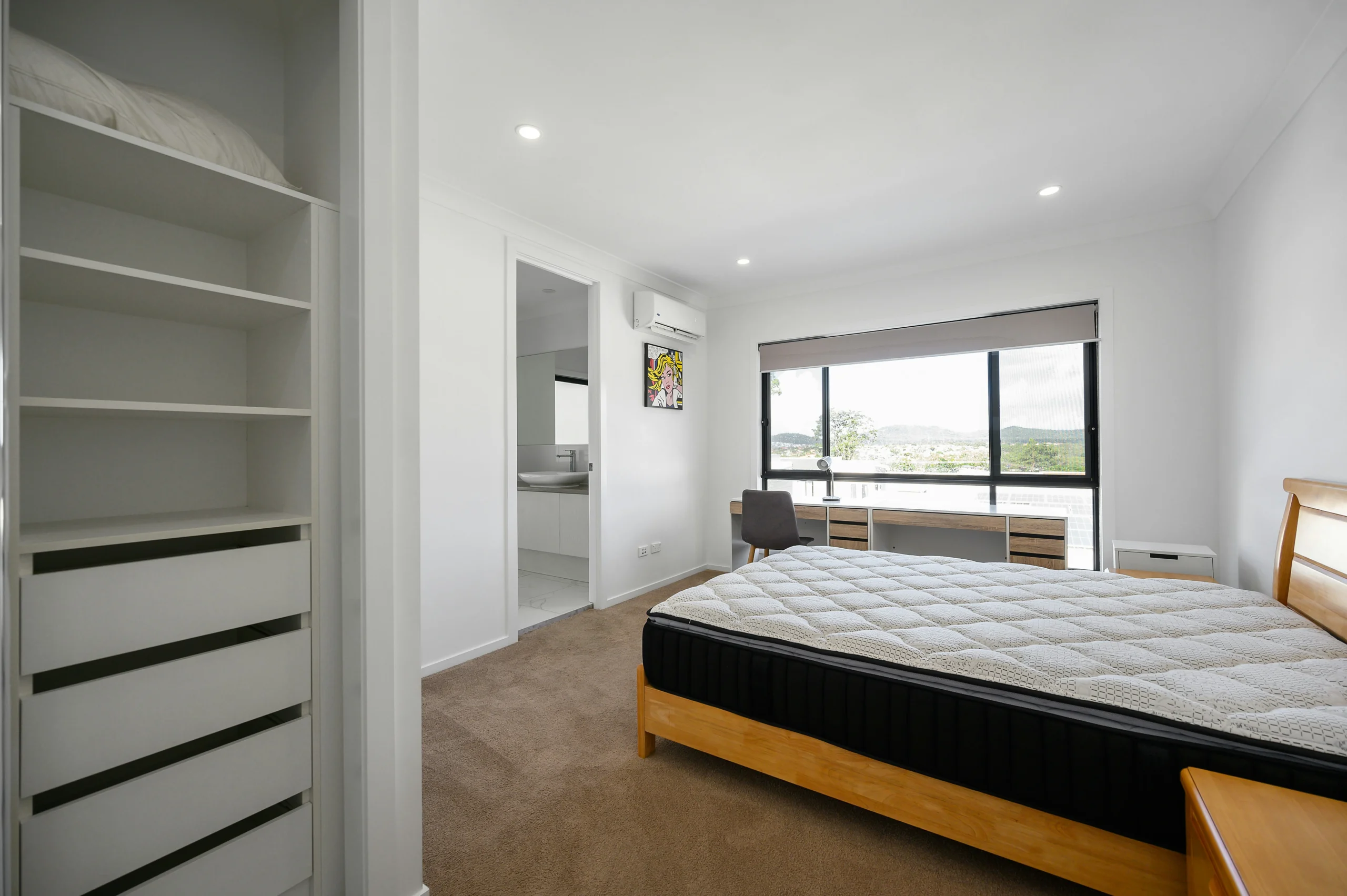 Chambre lumineuse avec un matelas posé sur un sommier solide, bien aérée grâce à une grande fenêtre